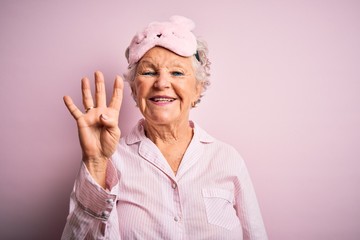 Senior beautiful woman wearing sleep mask and pajama over isolated pink background showing and...