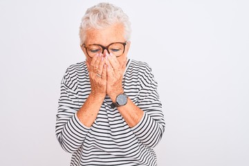 Senior grey-haired woman wearing striped navy t-shirt glasses over isolated white background with sad expression covering face with hands while crying. Depression concept.