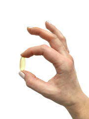 Woman s hand holding a capsule or pill of fish fat oil isolated on white background.