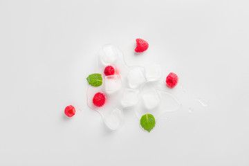 Ice cubes with raspberries and mint leaf on wooden table. Homemade skincare hydrating ice cubes....