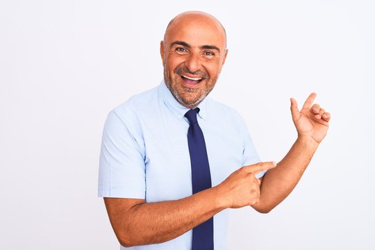 Middle age businessman wearing tie standing over isolated white background amazed and smiling to the camera while presenting with hand and pointing with finger.