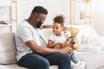 Little black girl playing with her handsome dad at home