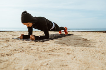 muslim woman doing core workout in park. Fit young woman exercising.
