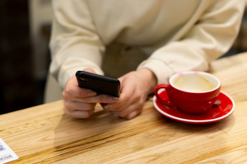 beautiful woman hands with mobile phone and coffee