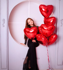young girl in a black dress with heart-shaped balloons