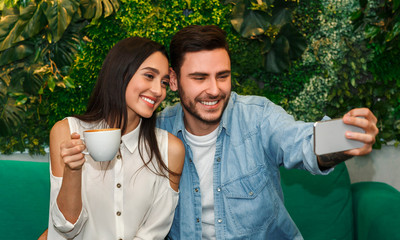 Cheerful Couple Making Selfie Hugging And Having Coffee In Cafeteria