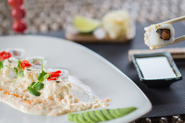 Traditional rolls with fish and rice on a white plate with sauce and wasabi. Japanese food.