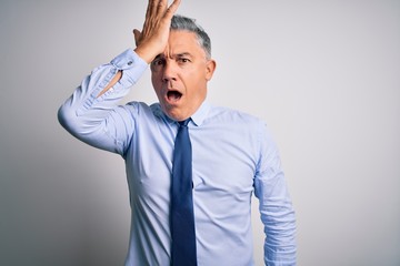Middle age handsome grey-haired business man wearing elegant shirt and tie surprised with hand on...