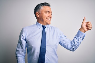 Middle age handsome grey-haired business man wearing elegant shirt and tie Looking proud, smiling doing thumbs up gesture to the side