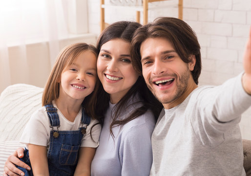 Happy Family With Cute Little Daughter Posing For Selfie At Home