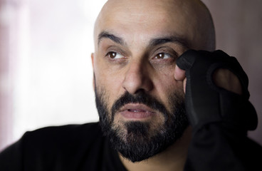 Bearded bald man wearing gym hand gloves thinking about something