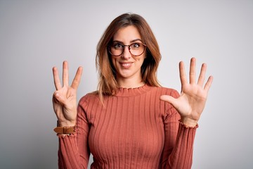 Young beautiful brunette woman wearing casual sweater and glasses over white background showing and pointing up with fingers number eight while smiling confident and happy.