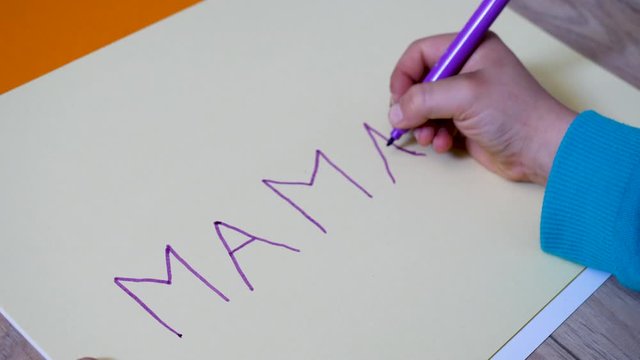 enfant qui écrit maman avec un feutre