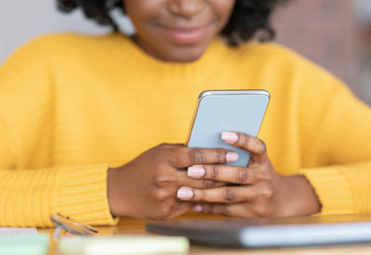 Cropped of black young woman holding smartphone