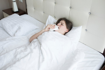 Ill woman with napkin lying under blanket in bed