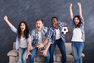 Excited multiethnic friends watching football at home