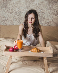 a cute girl is having a breakfast in her bed