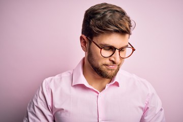 Young handsome blond man with beard and blue eyes wearing pink shirt and glasses with hand on stomach because indigestion, painful illness feeling unwell. Ache concept.