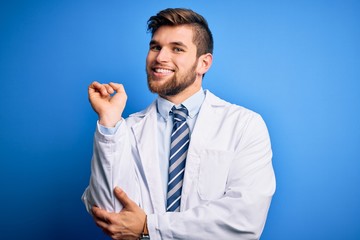Young blond therapist man with beard and blue eyes wearing coat and tie over background with a big smile on face, pointing with hand and finger to the side looking at the camera.