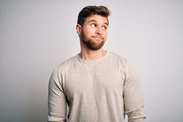 Fototapeta premium Young handsome blond man with beard and blue eyes wearing casual sweater smiling looking to the side and staring away thinking.