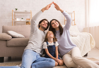 Caring parents making symbolic roof of hands above little daughter's head