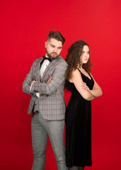 Irritated man and woman standing back to back with folded arms isolated on red background