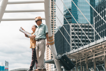 Fototapeta premium A couple of elderly Asian tourists visiting the capital happily and having fun and looking at the map to find places to visit.