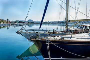 Fototapeta premium Yacht moored in the harbor of a quiet fishing town in a sunny, clear day. Sun glare.