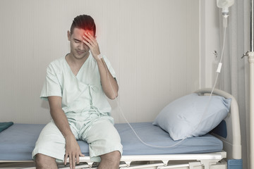 Young man is suffering from a headache pressing fingers to temples, closing eyes to relieve pain...