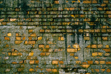 Old brickwall with crumbling concrete, moss and water damage