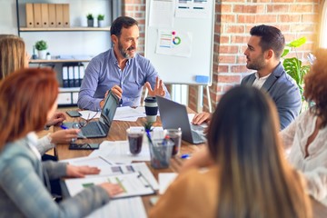 Group of business workers working together. Sitting on desk using laptop reading documents at the office