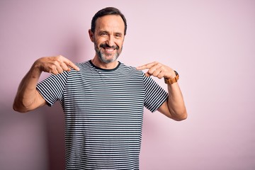 Middle age hoary man wearing casual striped t-shirt standing over isolated pink background looking confident with smile on face, pointing oneself with fingers proud and happy.