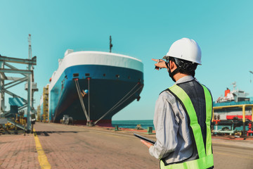 Naklejka premium foreman worker tablet in hand standing and pointing finger for target success front of vessel in shipyard tablet
