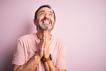 Middle age hoary man wearing casual t-shirt standing over isolated pink background begging and praying with hands together with hope expression on face very emotional and worried. Begging.