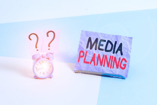 Handwriting text Media Planning. Conceptual photo the process of identifying and selecting media outlets Mini size alarm clock beside a Paper sheet placed tilted on pastel backdrop