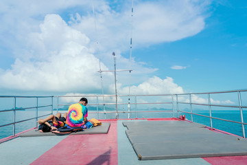 Tourists relaxing on boat deck and use smartphone on hot sunny day.