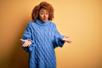 Young beautiful African American afro woman with curly hair wearing blue turtleneck sweater...