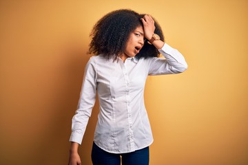 Young beautiful african american elegant woman with afro hair standing over yellow background...
