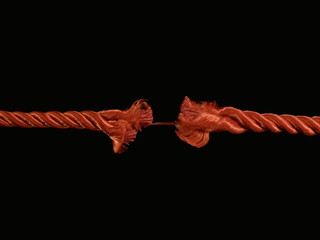The torn rope is about to break, a black background. The rope is held on one thread. Concept: life...