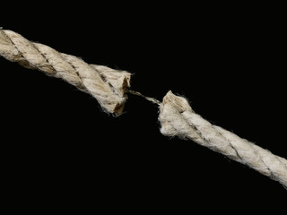 The torn rope is about to break, a black background. The rope is held on one thread. Concept: life...