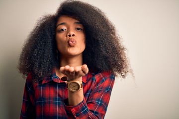 Young beautiful african american woman wearing casual shirt over isolated background looking at the camera blowing a kiss with hand on air being lovely and sexy. Love expression.