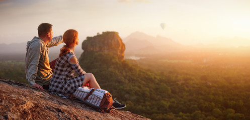 couple travelers watch a beautiful sunset near the famous rocky plateau Lion peak, Sigiriya. Sri Lanka - obrazy, fototapety, plakaty