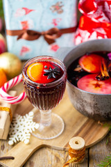 Mulled wine in a beautiful glass next to the saucepan. Hot drink in a glass. Christmas concept. Family evening with a hot drink. We cook mulled wine with apples and oranges. Hot wine.