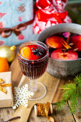 Mulled wine in a beautiful glass next to the saucepan. Hot drink in a glass. Christmas concept. Family evening with a hot drink. We cook mulled wine with apples and oranges. Hot wine.