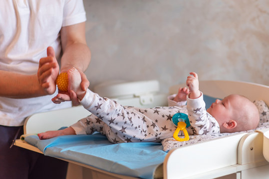 The Father Takes Care Of The Health Of The Child. Dad Makes A Ball Massage To His Newborn Baby.