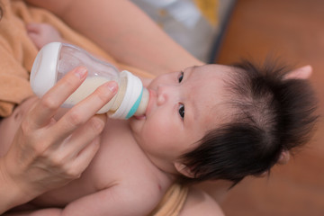 Obraz na płótnie Canvas Happy Asian mother feeds the cute newborn baby using bottle.