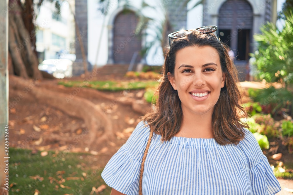 Wall mural Young beautiful woman smiling happy walking on city streets by the church on a sunny day of summer