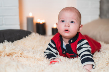 portrait of a handsome boy who lies on a fluffy carpet against the background of the fireplace