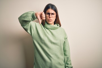 Young beautiful woman wearing casual sweater standing over isolated white background looking unhappy and angry showing rejection and negative with thumbs down gesture. Bad expression.