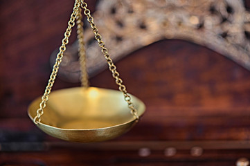 Close-up of an old gold scale with various decorations in a wooden box for storage.